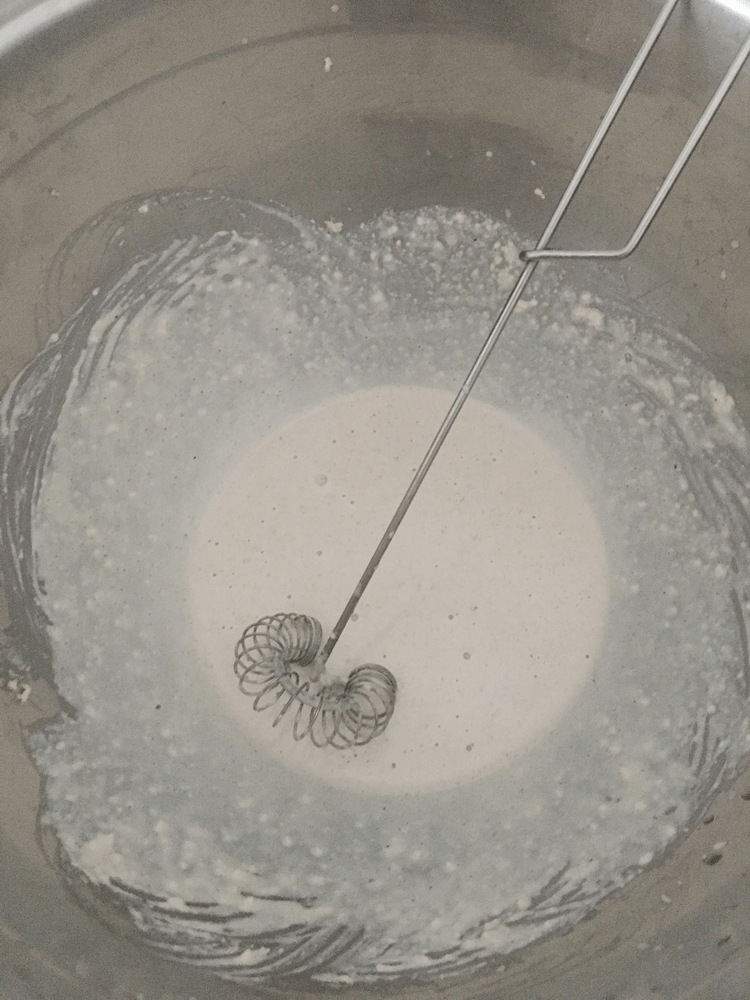A metal spoon is being used to stir a Real Food mixture in a bowl.