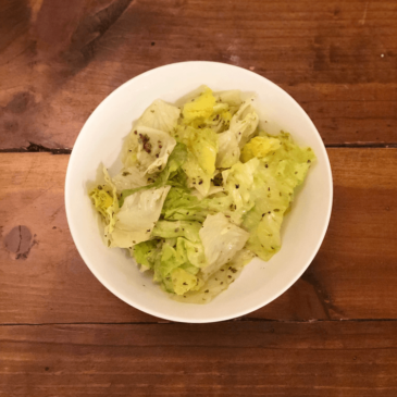 A bowl of fresh lettuce on a rustic wooden table.