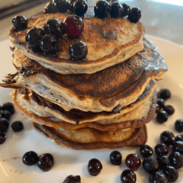 A stack of Real Food pancakes with blueberries on top.