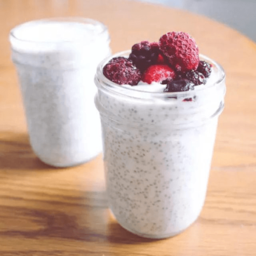 Two mason jars filled with nutritionist-approved chia pudding and fresh berries.
