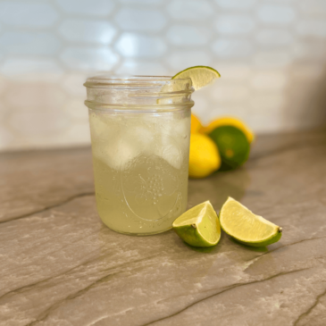 A mason jar filled with limes and ice, perfect for the health-conscious individual looking for real food options or seeking advice from a certified nutrition consultant.