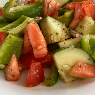 A plate of real food, curated by a nutritionist, featuring cucumbers, tomatoes, and onions.