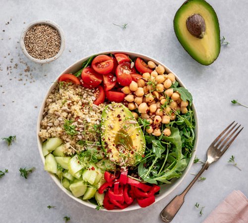 A bowl with quinoa, avocado, tomatoes, and cucumbers. This nutritious dish is perfectly balanced and packed with real food goodness. Perfect for health-conscious individuals looking to nourish their
